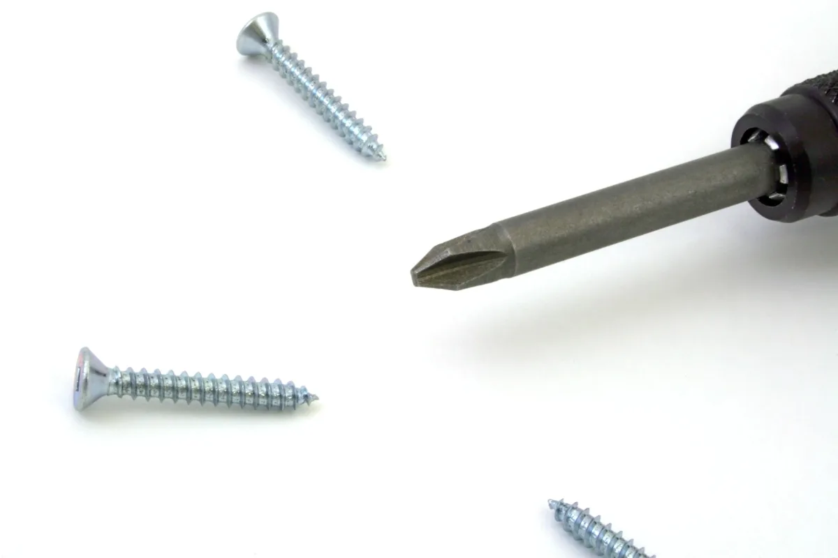 Close-up of screwdrivers and screws on a white surface